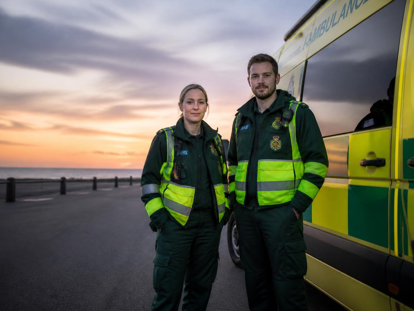 Ambulance crew in customised uniform beside an ambulance